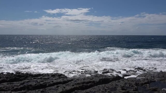 Sea waves crashing on volcanic rock coastline