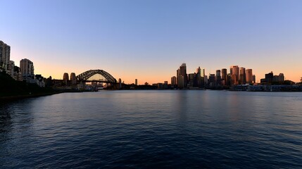 Obraz premium A serene cityscape unfolds under the soft golden light of the evening showcasing a majestic bridge and waterfront view