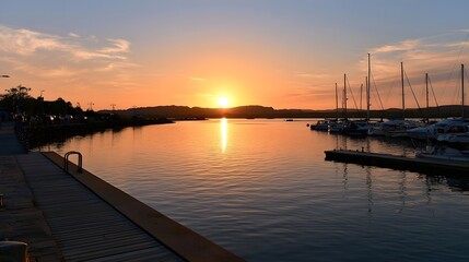 Fototapeta premium A wooden pier extends over calm water at sunset reflecting the golden hour light and creating a peaceful maritime landscape