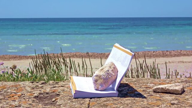 Open book with rock on beach by ocean