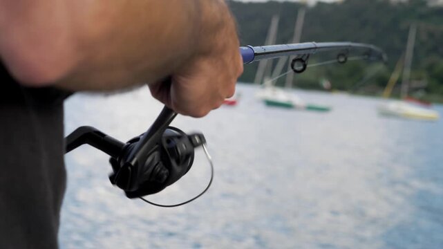 Close-up of a fisherman's hands skillfully operating the fishing reel during an active fishing session, capturing the precise and rhythmic movement of reeling in the line.