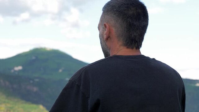 A compelling rear-view shot follows a fisherman as he casts his rod over a calm lake, revealing the full sweep of the cast and the expansive natural scenery stretching out before him.