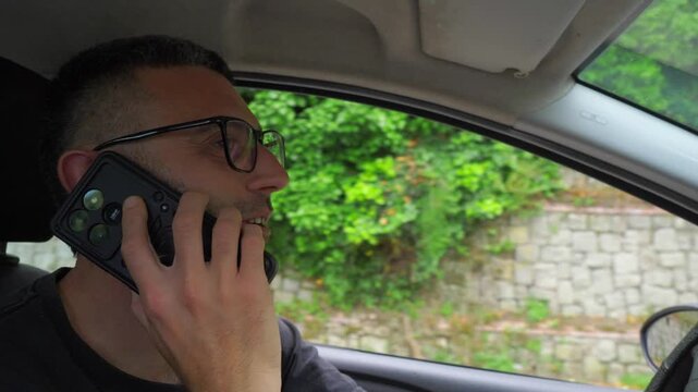 A young man casually talks on his phone while driving, ignoring traffic laws and distracting himself from the road, creating a serious danger for himself and surrounding traffic.