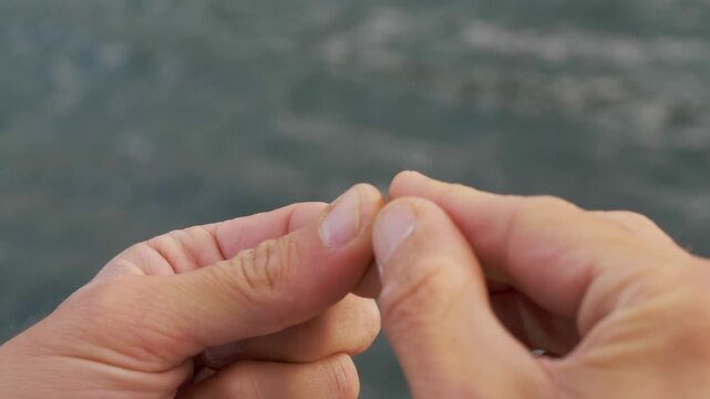 A fisherman carefully threads the main fishing line through the leader in a focused pre-fishing routine, ensuring all tackle components are properly connected for a successful cast