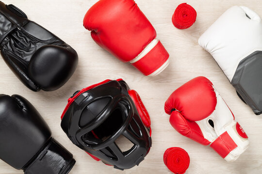 Boxing helmet and gloves on wooden background, top view.