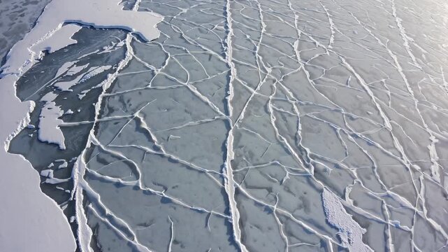 Ice floes and cracks in frozen sea surface create intricate patterns, showcasing the dynamic nature of polar environments in a cold climate landscape