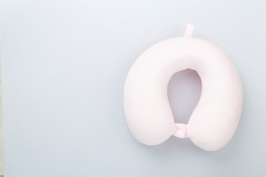 Pink travel pillow on color background, top view