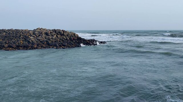 Calm yet powerful Arabian Sea water flowing around rocky breakwater at Gomti Ghat, Dwarka. Ideal for pilgrimage, sacred geography, coastal India, and spiritual documentary use.