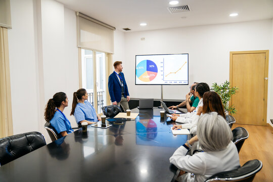 Medical team attending a business presentation in a conference room, analyzing charts and discussing healthcare strategy
