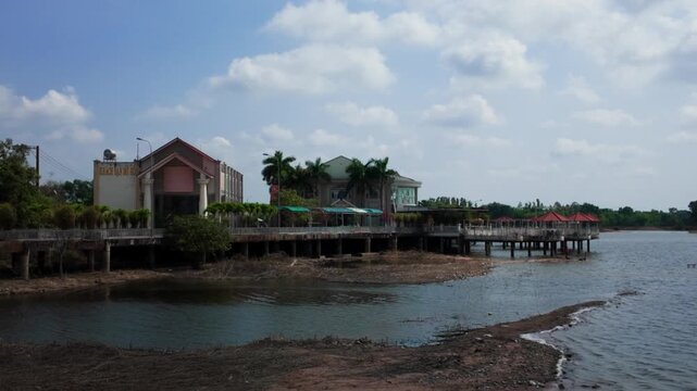 Visitors enjoy the outdoors at Cong Vien ven ho Ba To. The area features a view of the water, a pier, and buildings along the shore in Vung Tau.