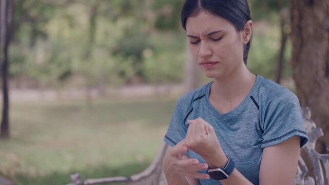 Young woman feeling numbness and tingling in fingers after outdoor workout in park, holding painful wrist, nerve pain and neuropathy health concept. numbness, tingling, fingers, nerve, neuropathy.	
