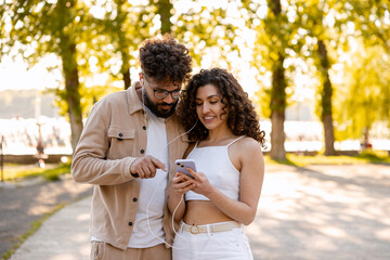 Fototapeta premium Young couple sharing earphones for music on smartphone