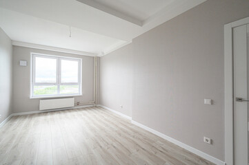Fototapeta premium bright empty room with light grey textured walls, light wood laminate flooring, a large double window with a white radiator below, and white ceiling