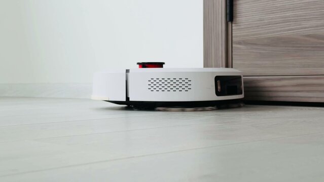 Robotic vacuum cleaner navigating smooth floor near door threshold with contemporary design