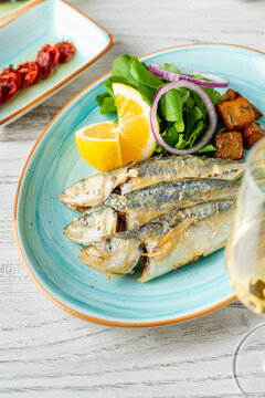 Grilled horse mackerel served with lemon, onion and greens in Mediterranean style presentation