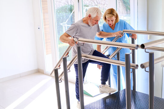 Senior Man Climbing Stairs With Physiotherapist Assistance During Rehabilitation Exercise Indoors In Rehab Center For Recovery And Strength Training