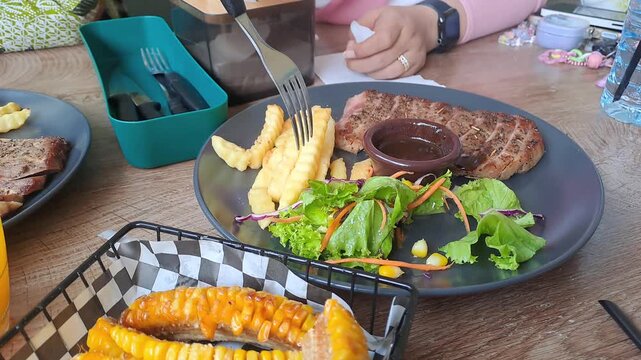 Gourmet steak house platter featuring Rib Eye, Sirloin, and Ribs Corn with a large double-meat burger. Cinematic camera movements from close-up to eagle eye view. Luxury dining experience. 4K.