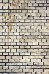 Fototapeta premium Close up view of an old weathered brick wall. Light colored bricks show dark mortar lines and vertical brown dirt streaks