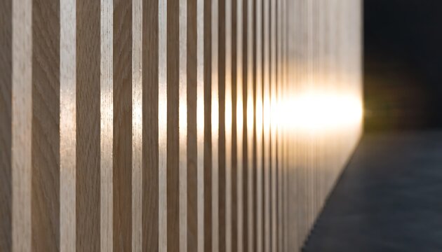 Close-up of a wooden slatted wall with warm sunlight reflecting off the surface, creating a textured and abstract pattern with soft light and