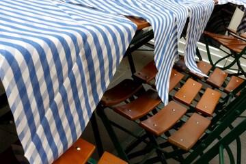 Fototapeta premium Blue and White Striped Tablecloths on Wooden Outdoor Seating for Cafes and Restaurants