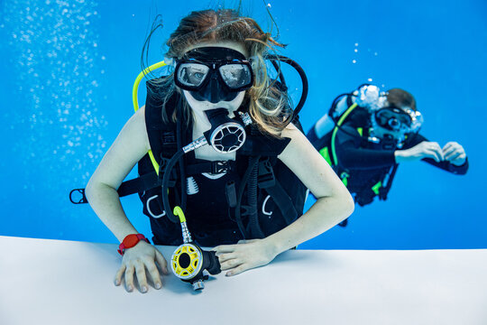Underwater view of a scuba diving instructor and a teenage girl student training in a deep swimming pool