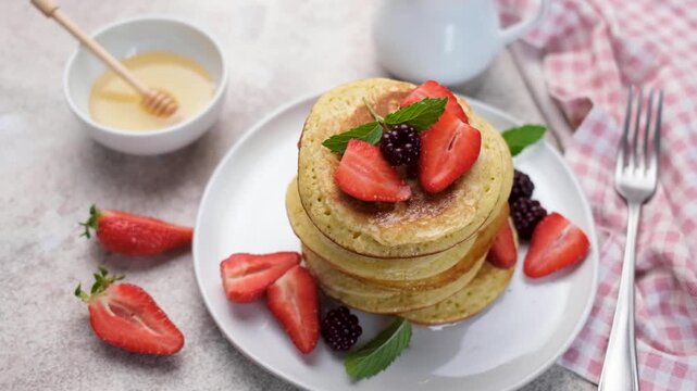 Stack of pancakes with fresh berries and honey