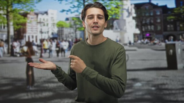 Young man with open palm and pointing finger gestures while speaking in a crowded street plaza; informative persuasion.