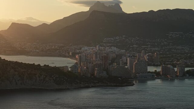 Calpe skyline at sunrise with bay waterfront and mountain silhouettes aerial city view Spain