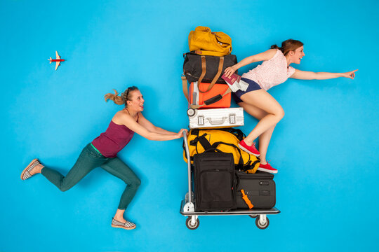 Friends pushing luggage trolley, hurrying for departure