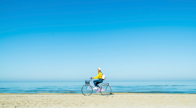 Young woman riding bicycle at beach on sunny day