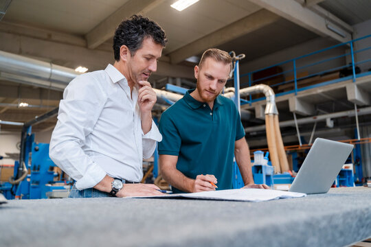 Two carpenters talking over documents in production hall