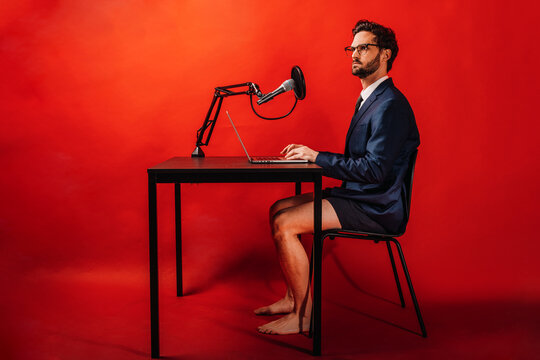 Businessman using laptop at desk by red background