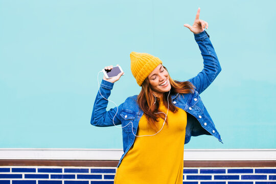 Dancing young woman wearing yellow cap and dress