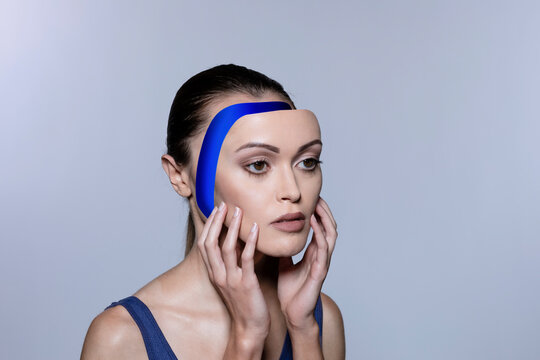 Female robot removing face panel against white background