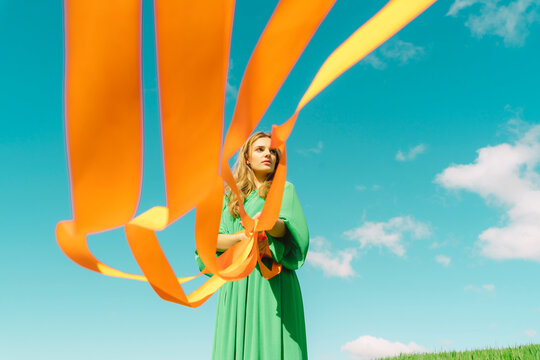 Young woman wearing a green dress holding orange ribbons