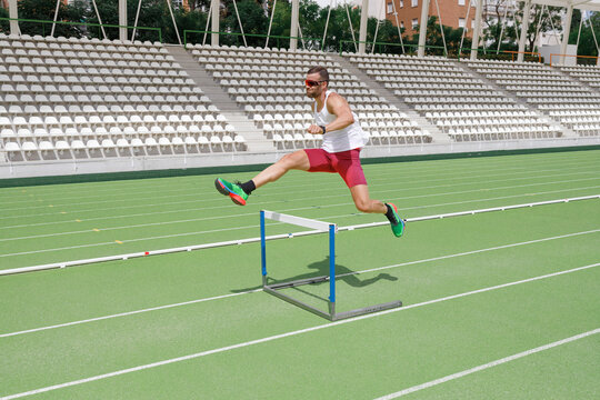 Athlete jumping over hurdle on sports track