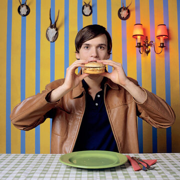 Young man eating burger, portrait