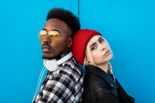 Portrait of young couple back to back against blue background
