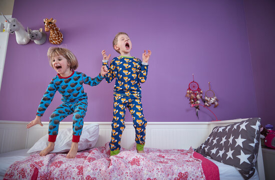 Brother and sister wearing pajamas romping around in children's room