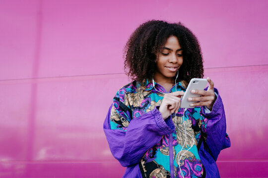 Young woman typing on smartphone and listening to music