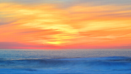 Obraz premium Sunset over the Atlantic Ocean on the Camino de Santiago, emphasising the movement of the clouds and the waves.