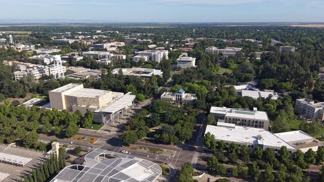 Aerial perspective showcasing the sprawling campus of the University of California, Davis, highlighting its modern architecture, lush green spaces, and academic buildings under a clear sunny day