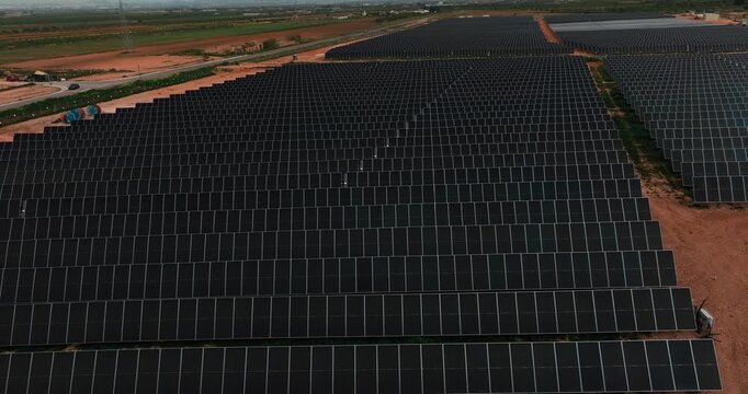 Drone view of expansive solar farm with rows of photovoltaic panels generating renewable electricity in rural landscape. Clean energy infrastructure and sustainable power production.