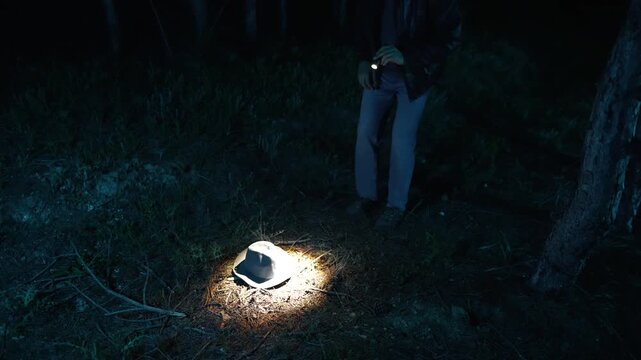 Detective finds hat in forest at night and picks it up
