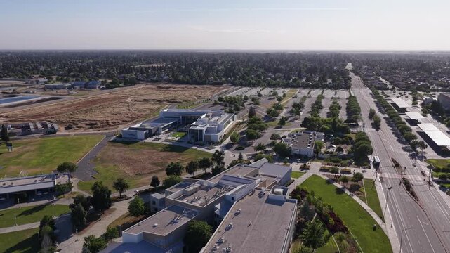 Sunny day aerial view of the Clovis Community College campus buildings, parking lots, and surrounding cityscape in Fresno, California, showcasing the modern architecture and green spaces