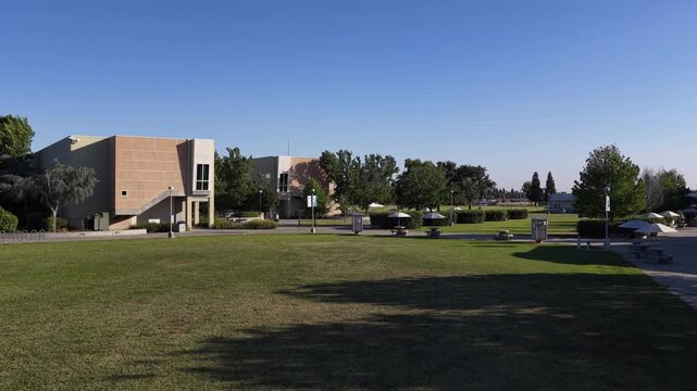 Drone view slowly rising over the modern campus of Clovis Community College in Fresno. California. Revealing the buildings. Green lawns. Parking lots with solar panels. And the surrounding landscape