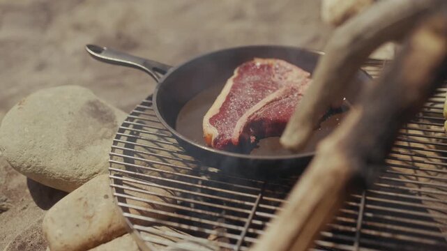 Cooking a T-bone steak in a cast iron pan outdoors
