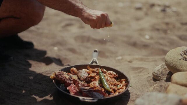 Squeezing lime juice over a cast iron pan on the beach