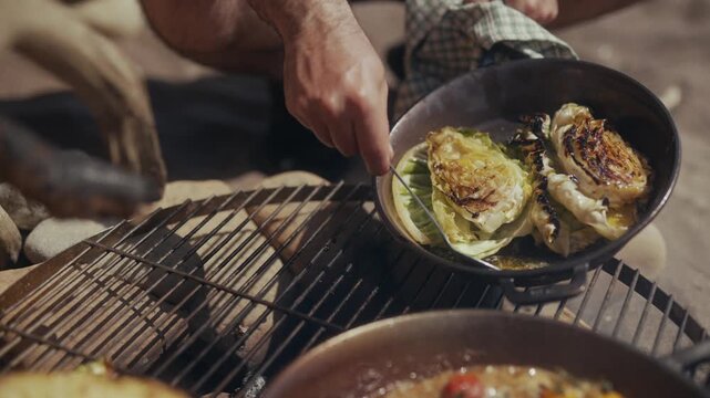 Cooking grilled cabbage in a cast iron pan over a fire pit