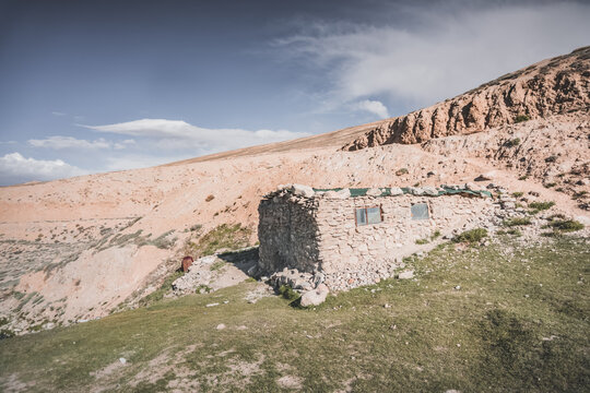 A stone building in the Tien Shan Mountains in the Pamirs, against the backdrop of rocky slopes